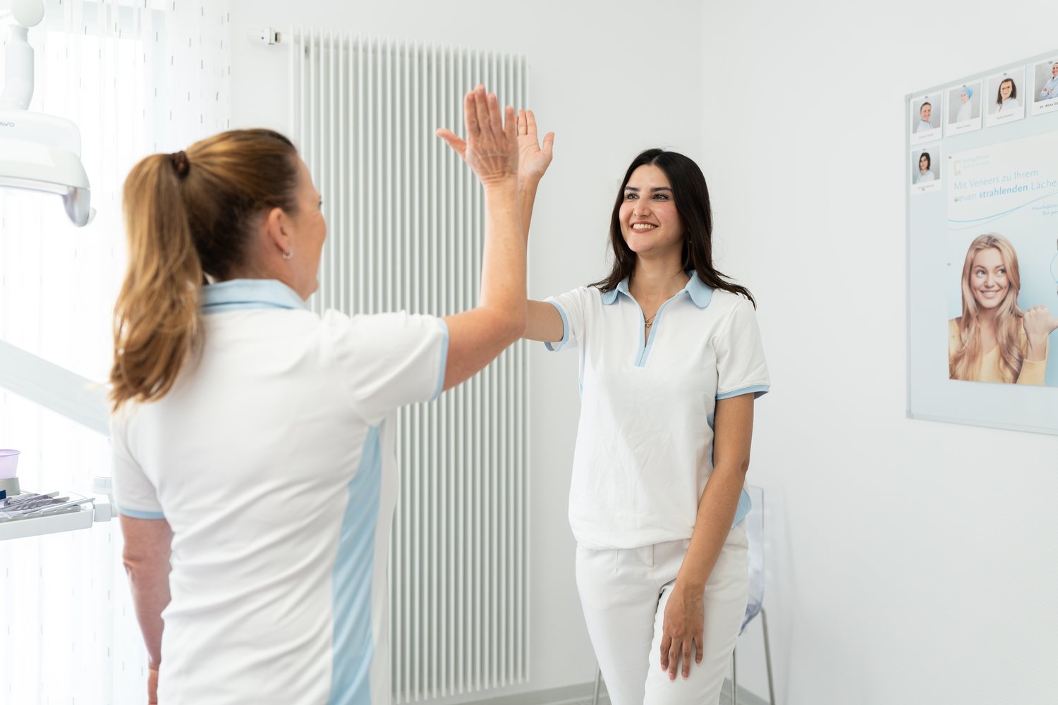 Zwei Kolleginnen klatschen sich im Behandlungszimmer ab